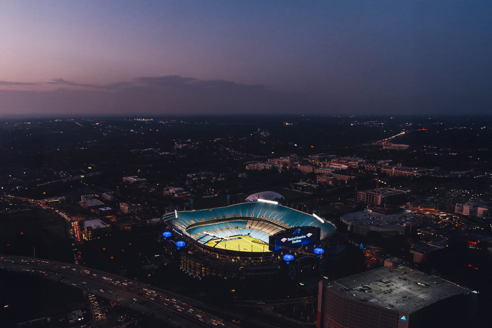 Aerial night view of Carolina Panthers stadium lit up surrounded by the Charlotte NC cityscape for a Redefined video production project