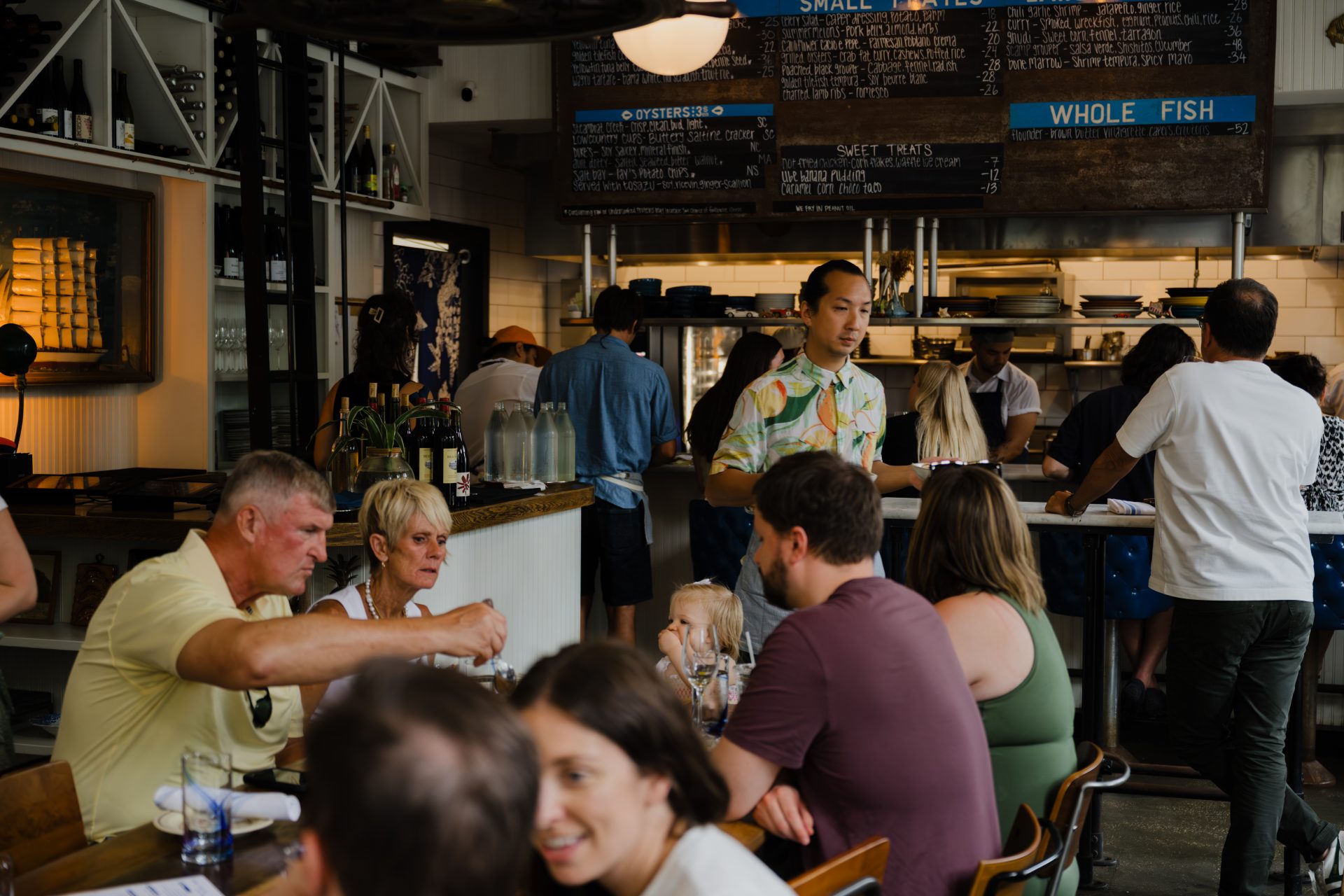 Lively restaurant dining scene at Chubby Fish Charleston with guests enjoying meals in a warmly lit interior setting