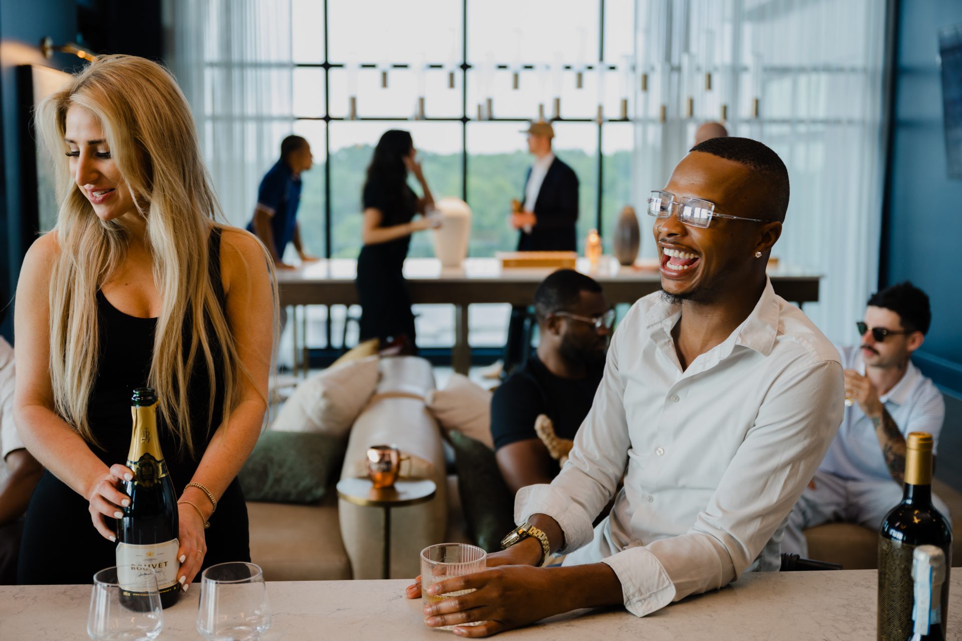 Couple sharing drinks and laughing together in a social lounge at The Rowe luxury apartments Plaza Midwood