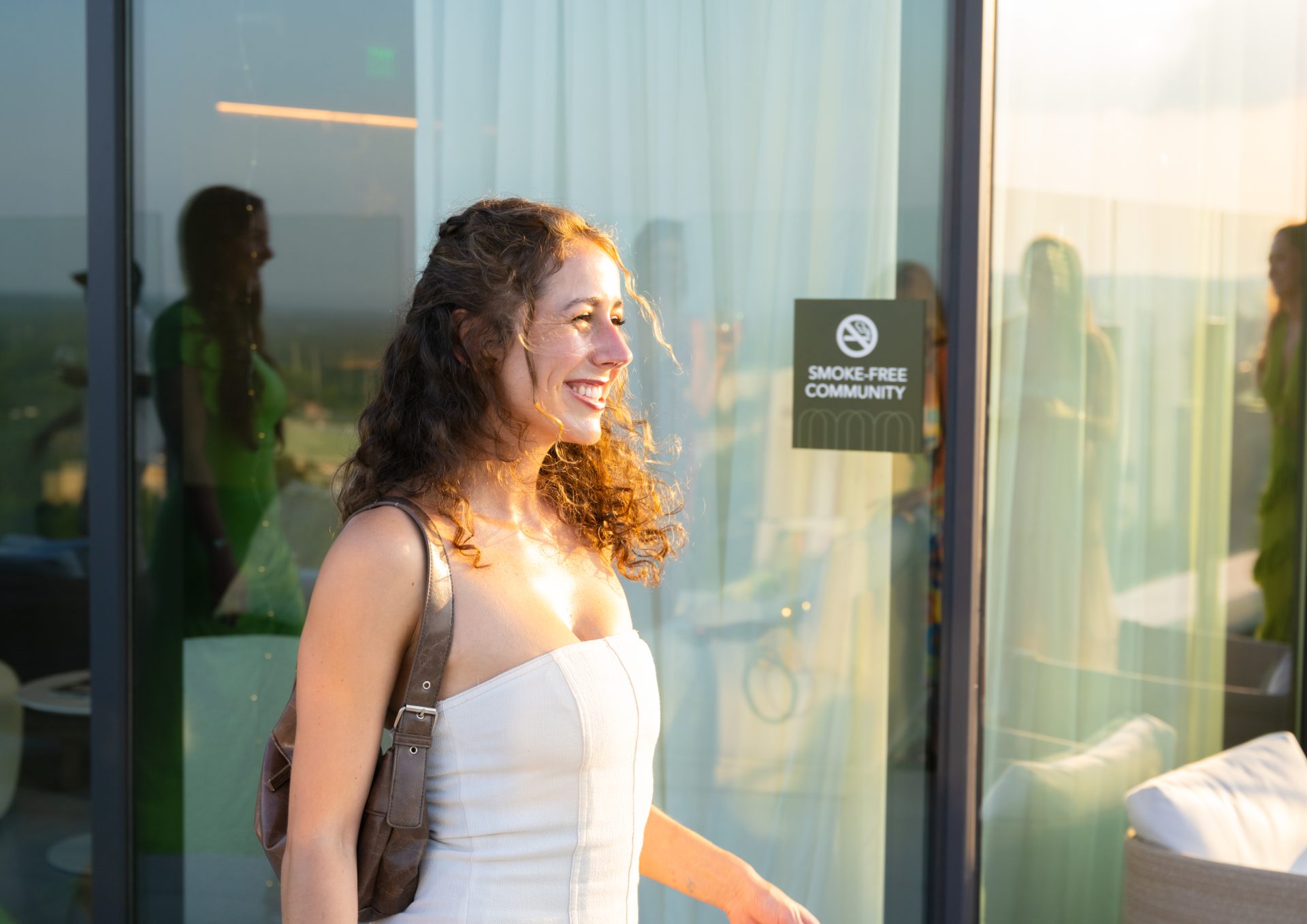 Smiling woman in white top standing in a bright modern apartment entryway