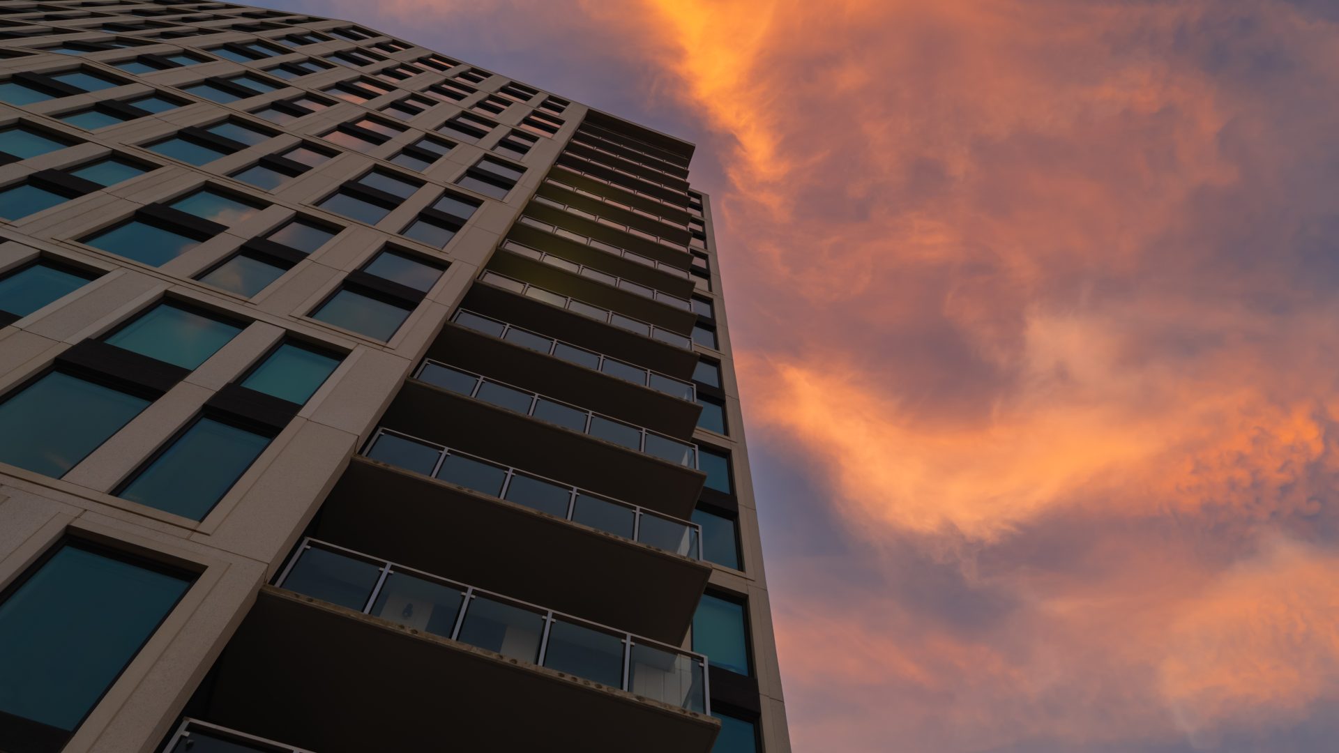 High-rise apartment building facade against a dramatic sunset sky