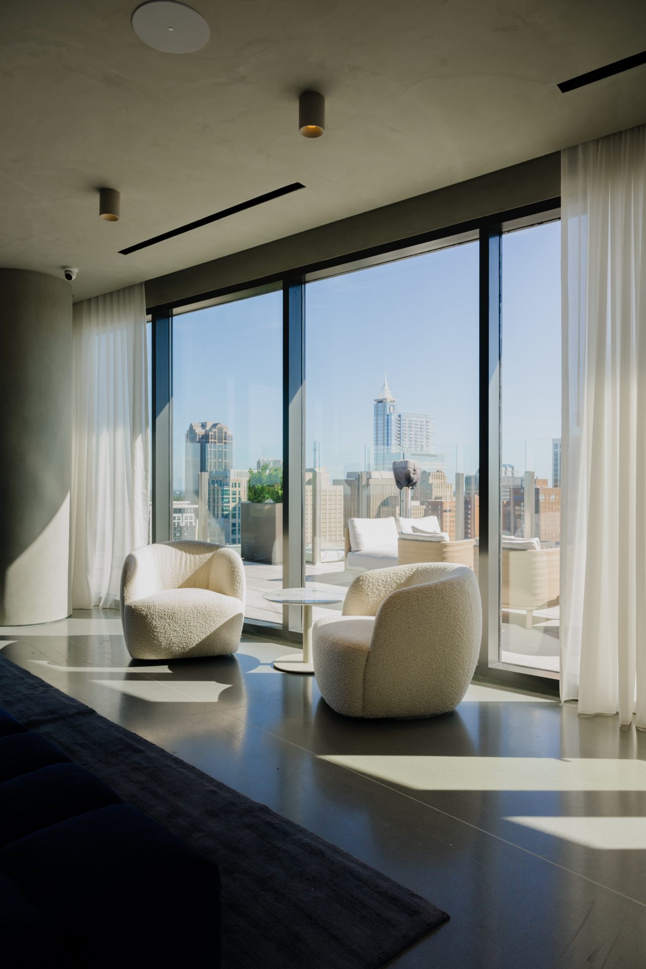Sleek apartment living room with floor-to-ceiling windows and city views at dusk