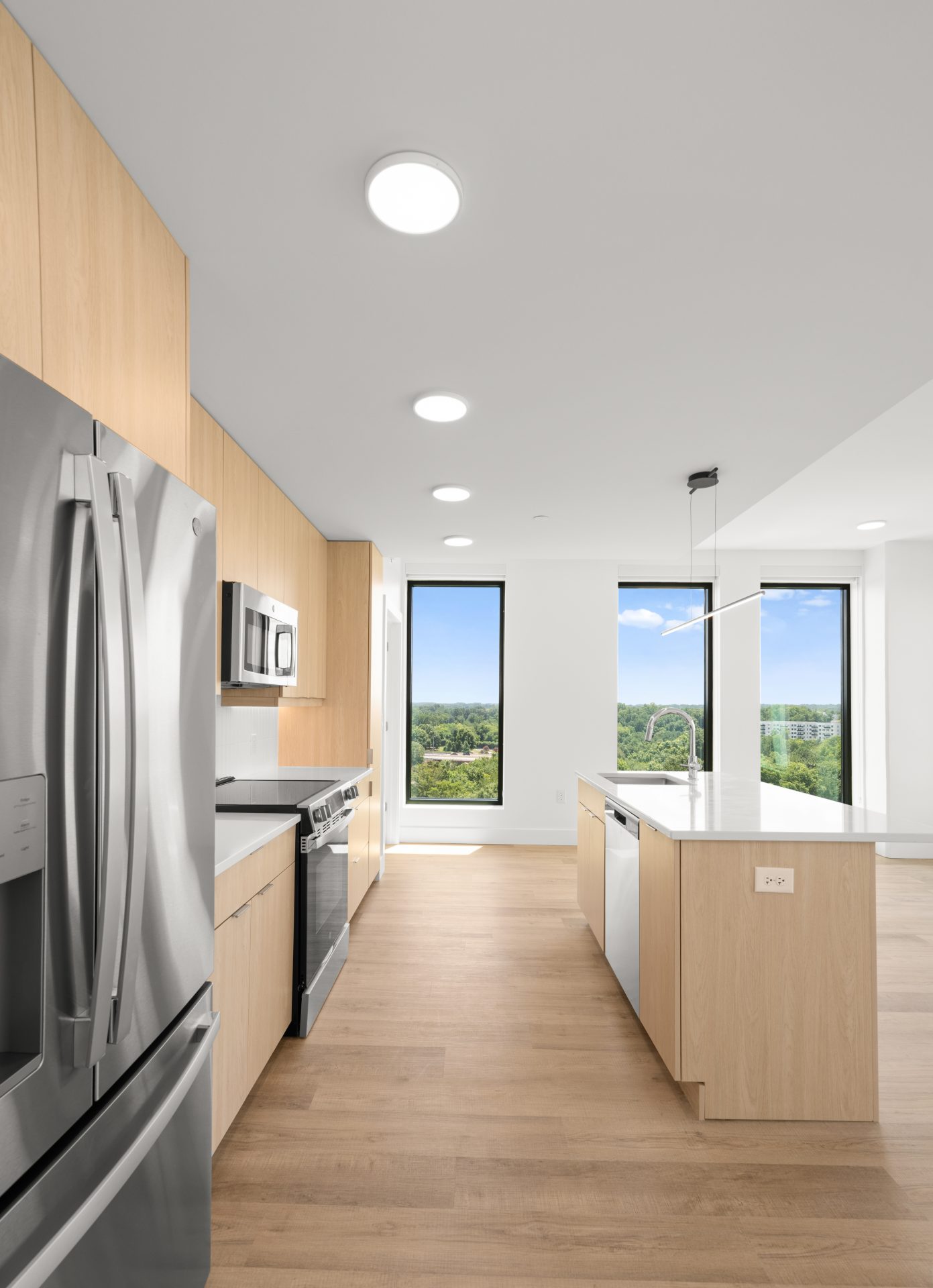 Bright modern apartment kitchen with white cabinetry and city views