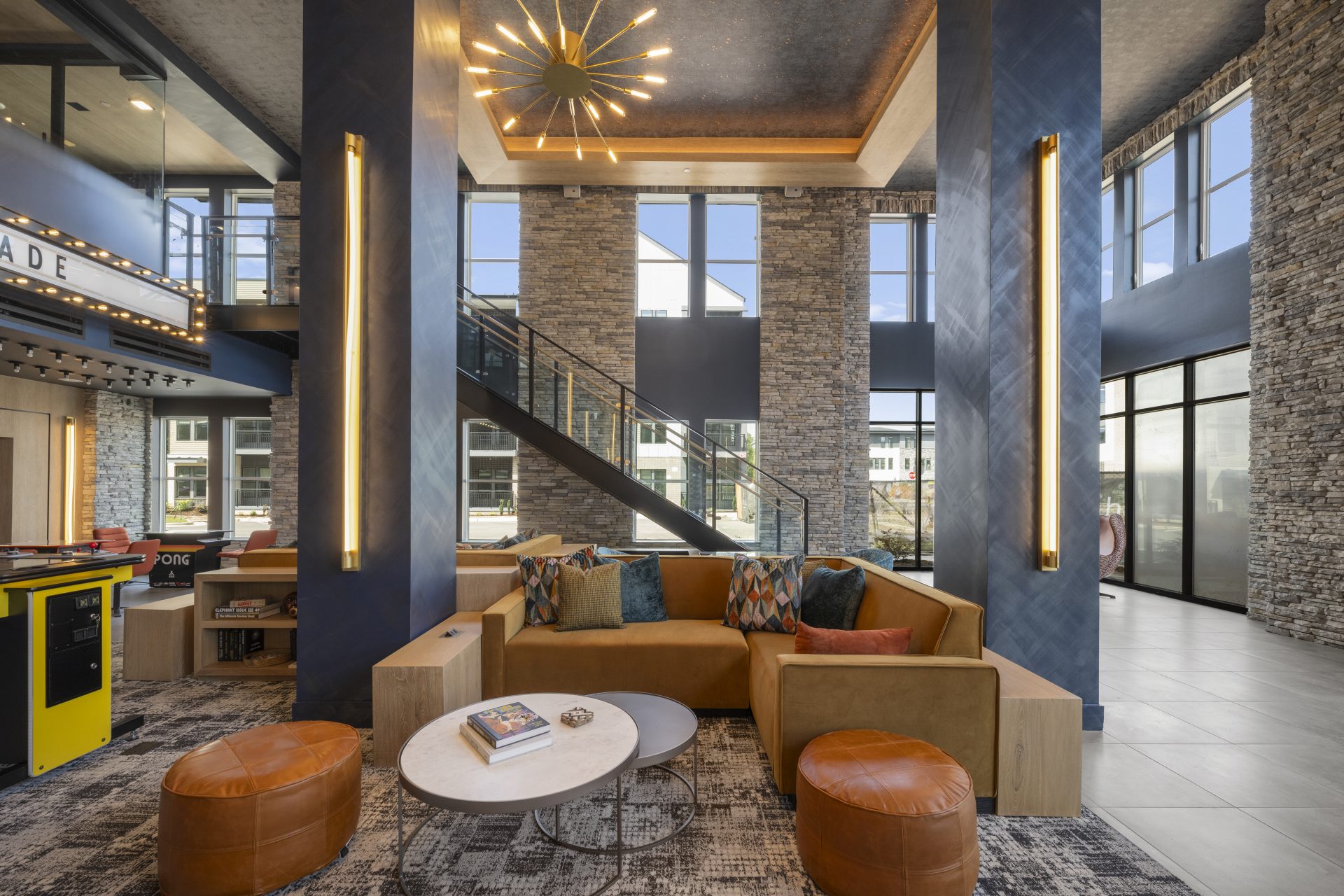 Elegant apartment lounge with a statement chandelier, leather ottoman, and large windows