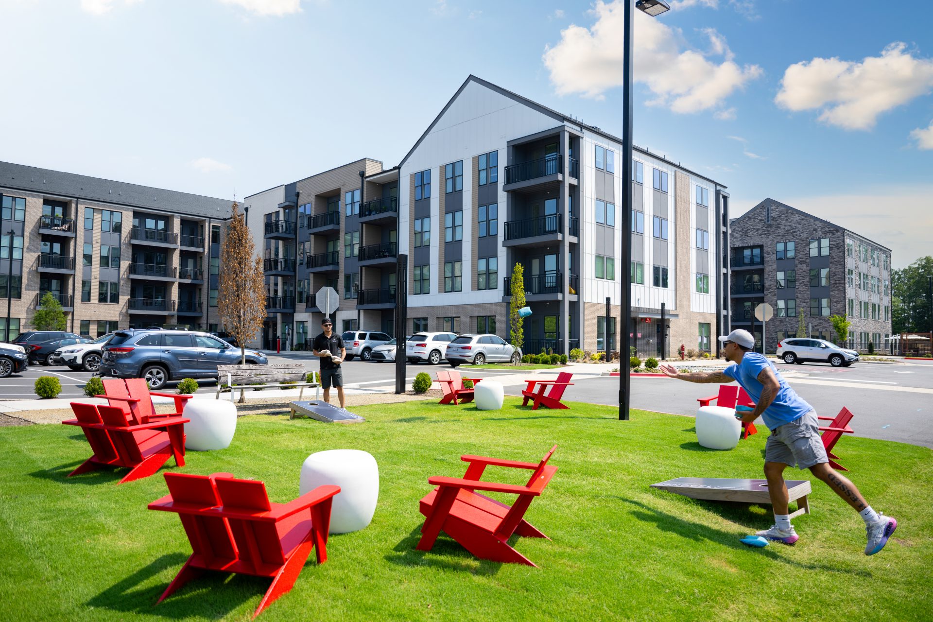 Residents relaxing on red lounge chairs on a green outdoor lawn
