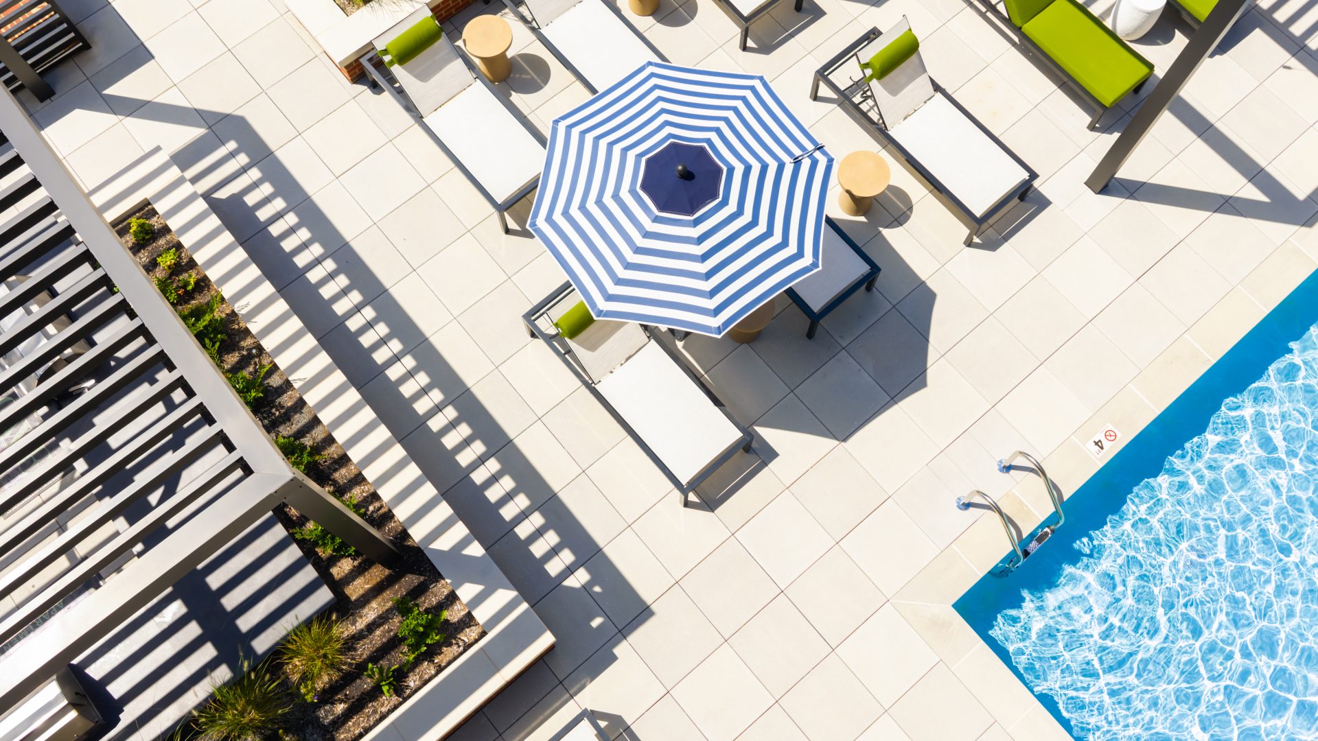 Aerial view of resort-style pool deck with lounge chairs and umbrellas