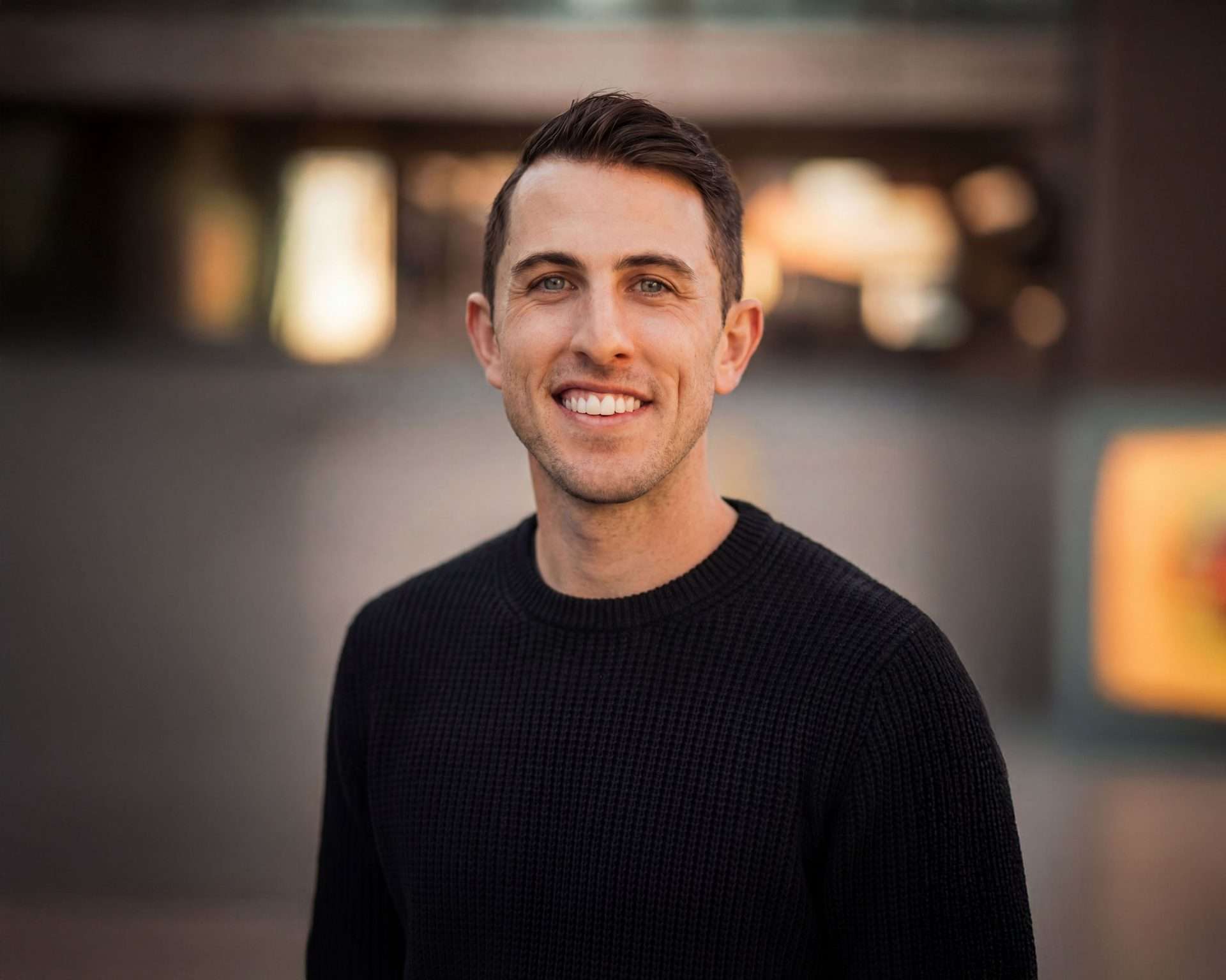 Kevin McGevna, Editor and Colorist at Redefined, smiling in a casual dark outfit with a warm blurred background