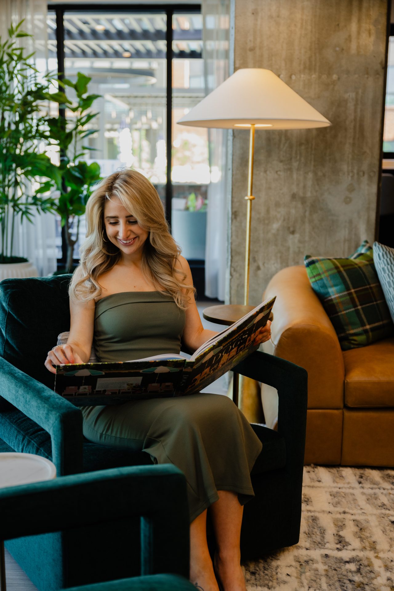 Resident reading on a velvet chair next to a statement floor lamp in a luxury apartment